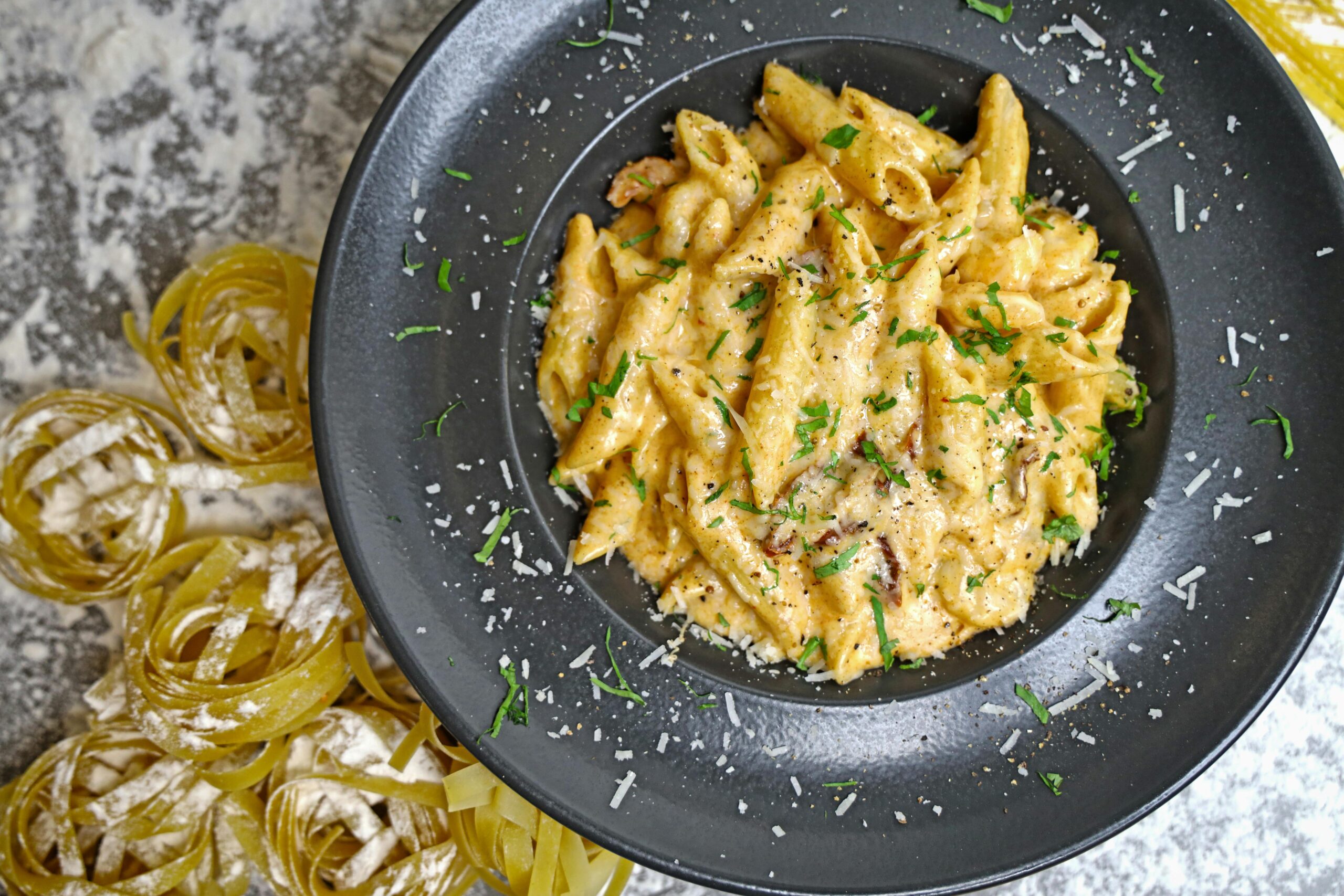 Delicious creamy penne pasta garnished with cheese and parsley.